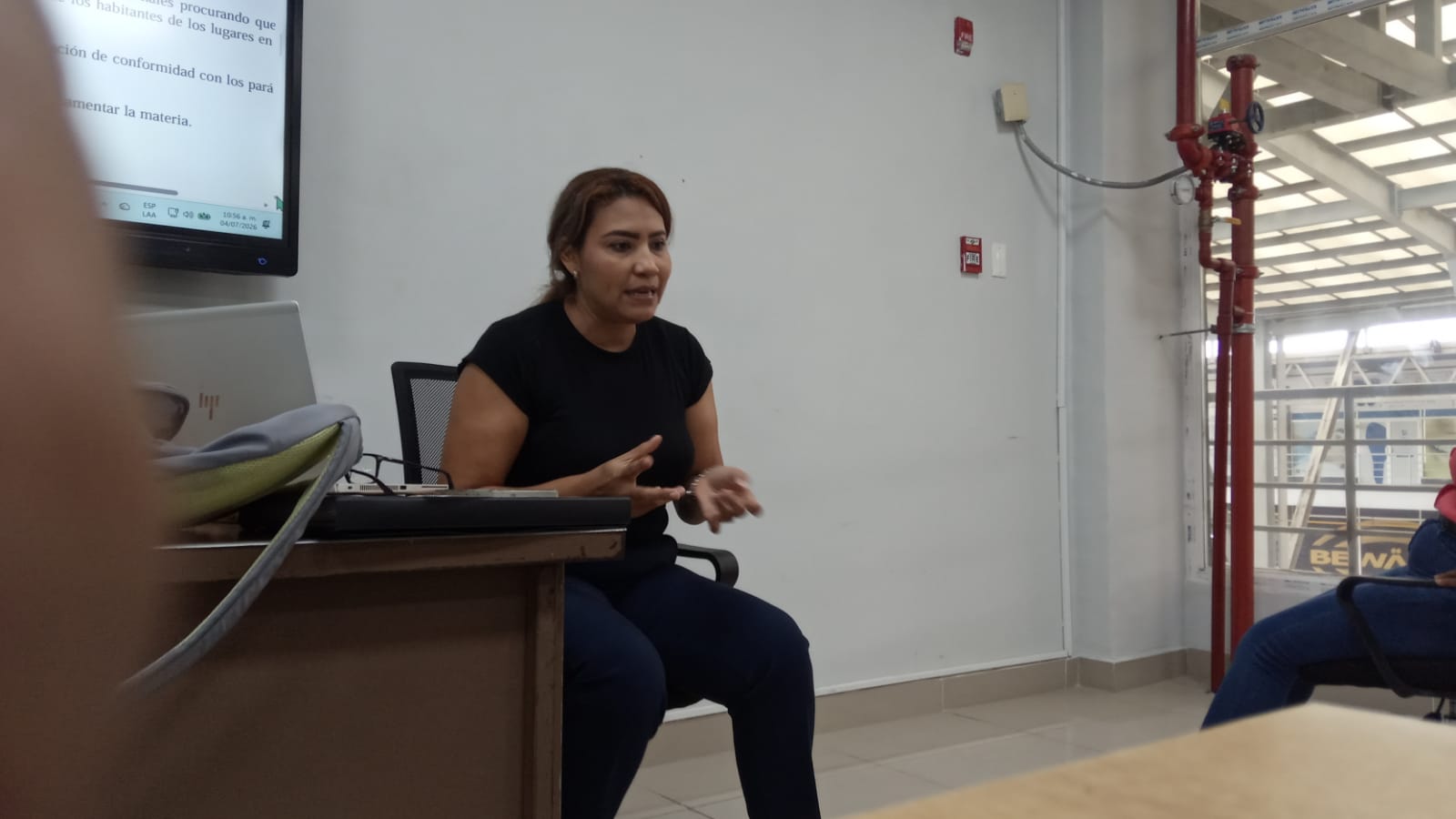 La Magíster Ana Rivera durante el conversatorio del 7 de abril de 2026 en INADEH Mañanitas — gesticula explicando un concepto, el proyector encendido a su izquierda