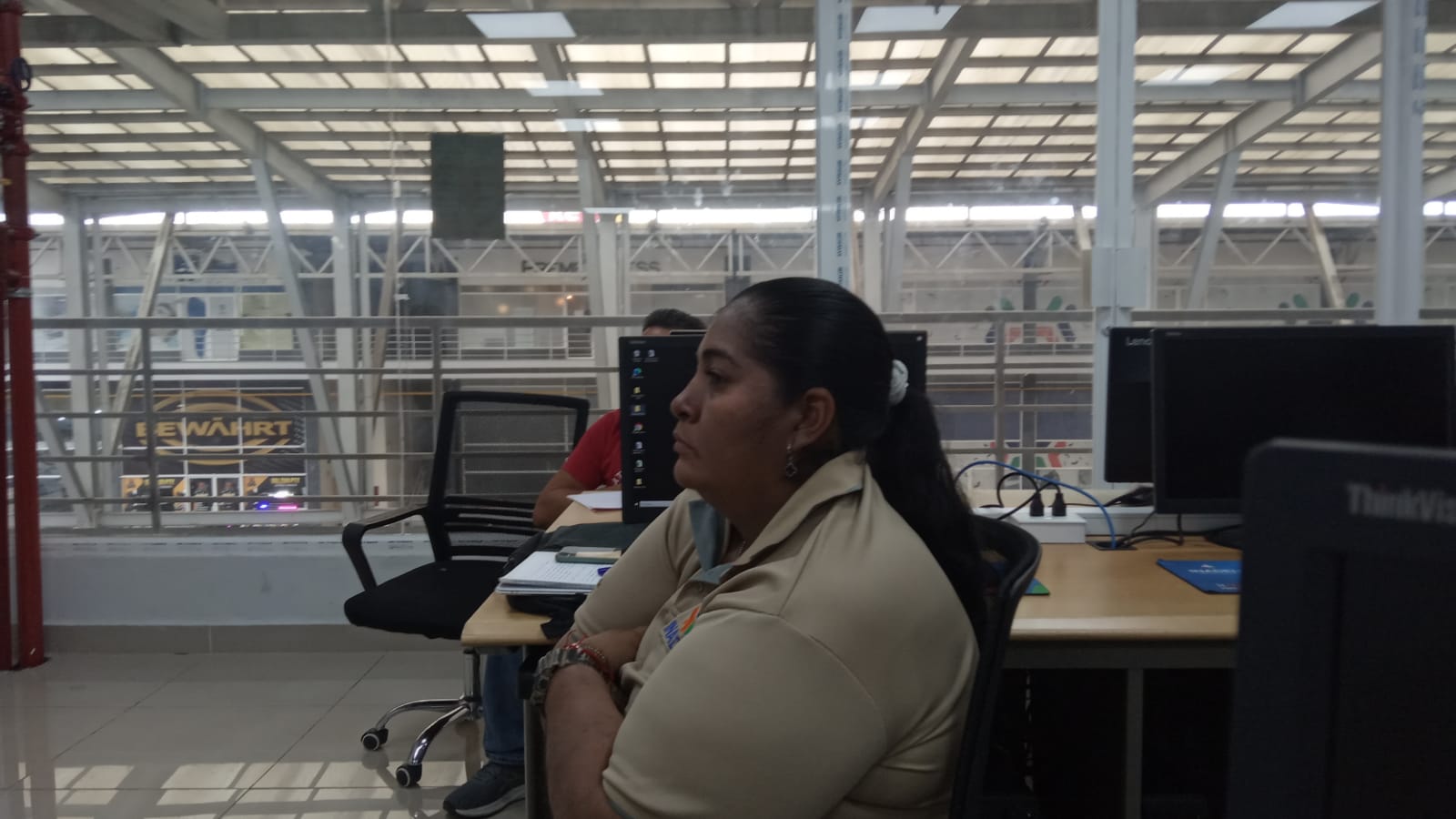 Angélica Pitti escuchando atentamente en el Salón 18 INADEH — fondo de ventanales industriales del centro comercial